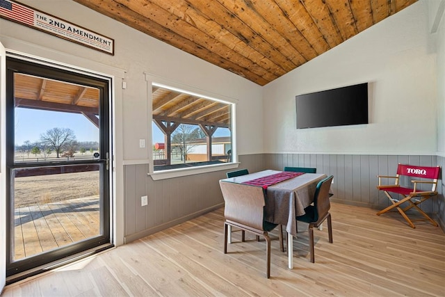 dining area featuring lofted ceiling, wood ceiling, a wainscoted wall, and wood finished floors