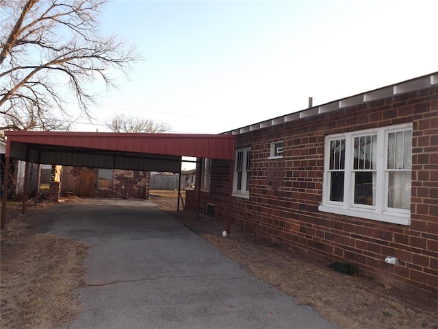 view of side of property with a carport, aphalt driveway, and brick siding