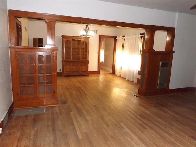 unfurnished living room featuring ornate columns, baseboards, visible vents, and wood finished floors