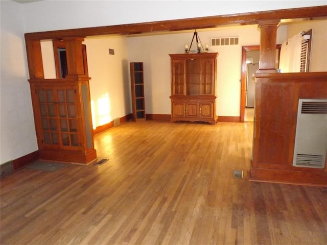 unfurnished living room with baseboards, light wood-type flooring, visible vents, and heating unit