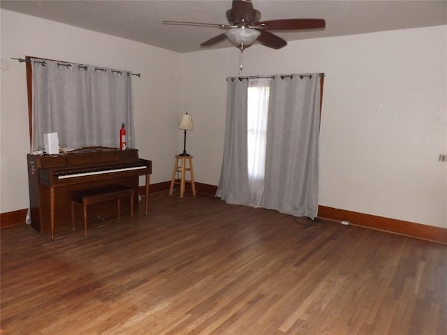 living area with ceiling fan, dark wood finished floors, and baseboards