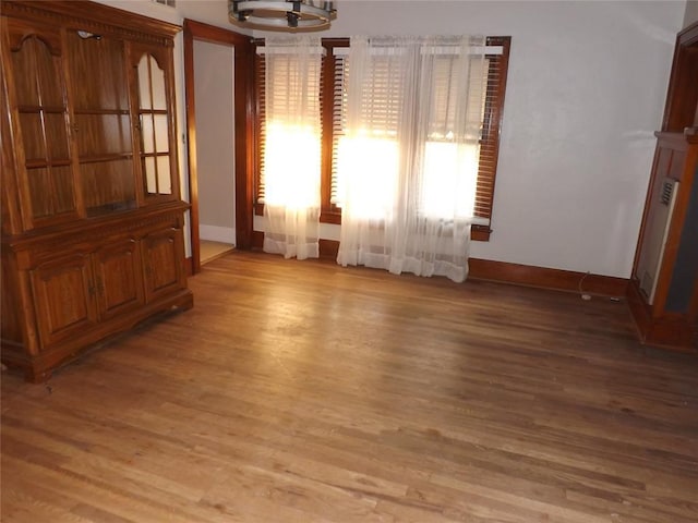 empty room with light wood-type flooring and baseboards