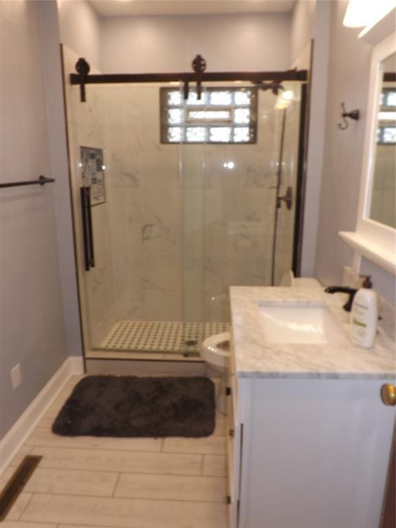 bathroom with toilet, a wealth of natural light, a marble finish shower, and vanity