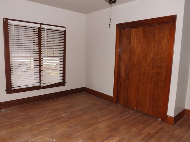 empty room featuring baseboards and dark wood-type flooring