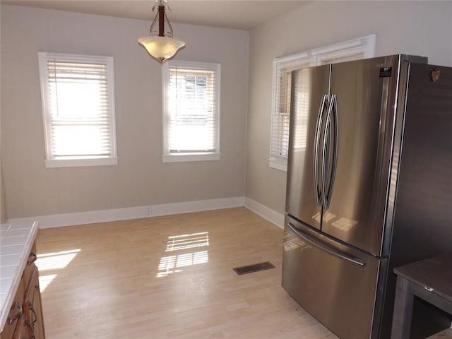 kitchen featuring tile countertops, a wealth of natural light, hanging light fixtures, and freestanding refrigerator