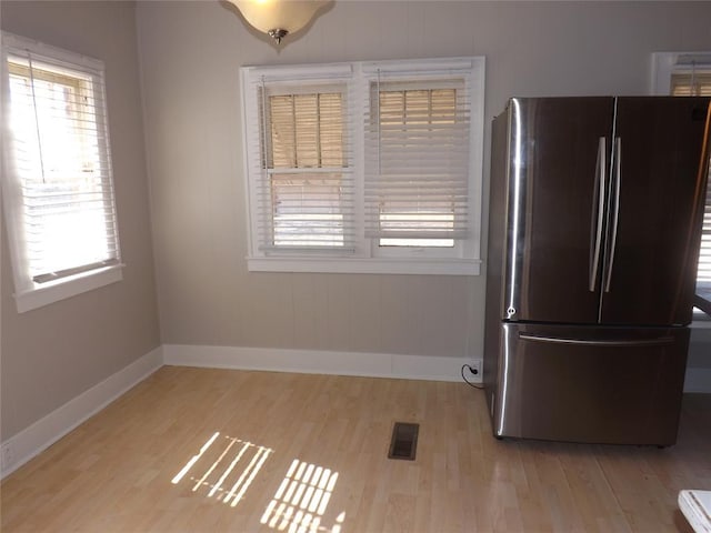 interior space featuring light wood-style floors, baseboards, visible vents, and freestanding refrigerator