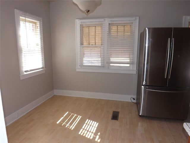 unfurnished dining area featuring visible vents, light wood-style flooring, and baseboards