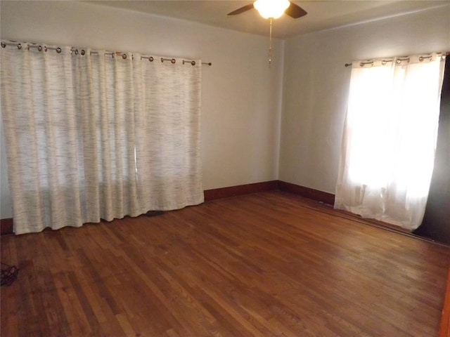 unfurnished room featuring ceiling fan, baseboards, and dark wood-style flooring