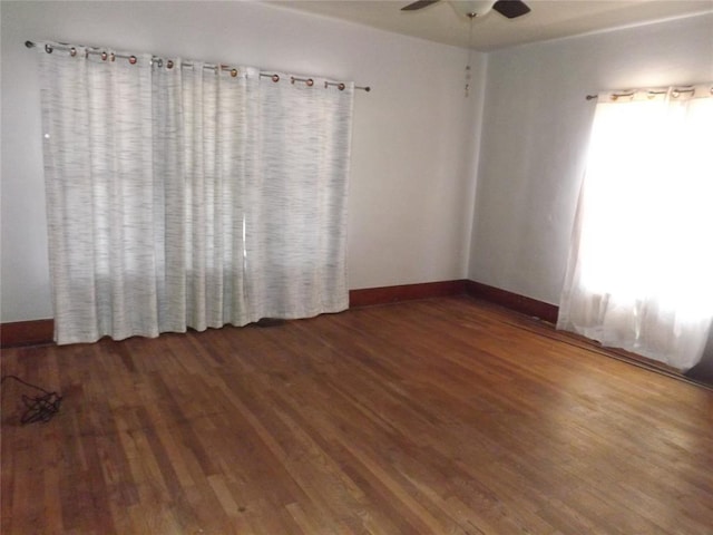 unfurnished room with dark wood-type flooring, ceiling fan, and baseboards