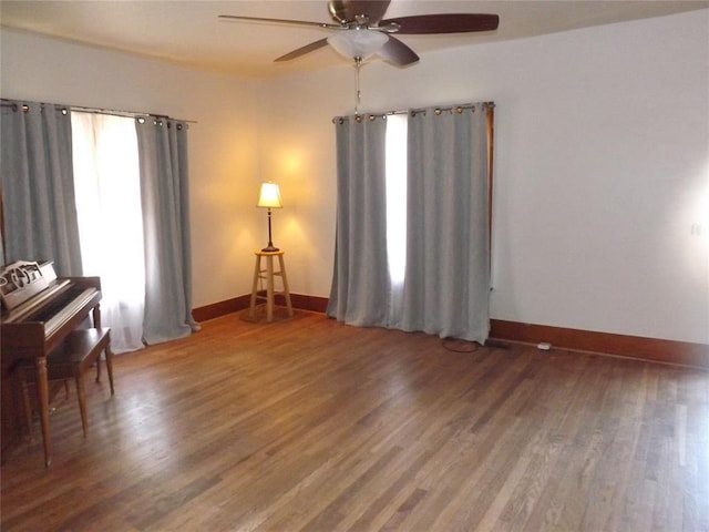 interior space featuring dark wood-style floors, baseboards, and a ceiling fan