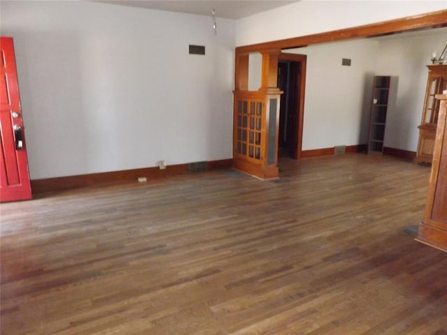 unfurnished living room with dark wood-style floors, visible vents, and baseboards