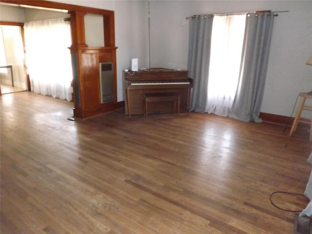 unfurnished living room featuring baseboards and dark wood-type flooring