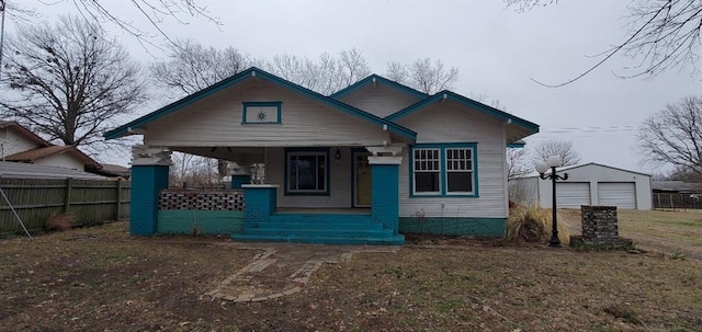 view of front of home with a garage, fence, a porch, and an outdoor structure