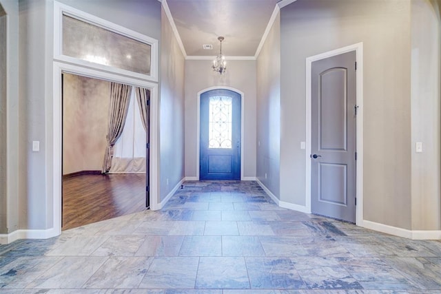 foyer featuring a chandelier, crown molding, and baseboards