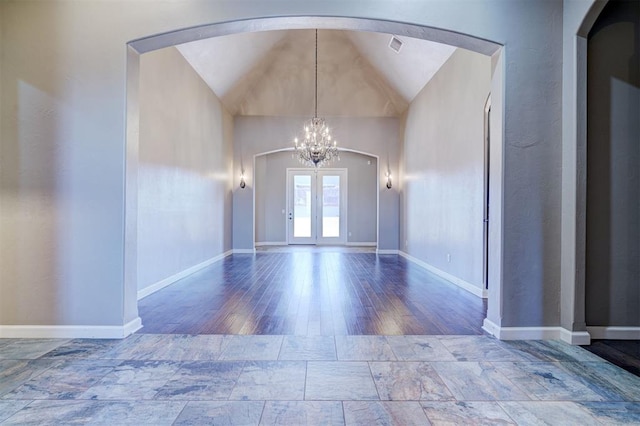 foyer entrance with lofted ceiling, baseboards, arched walkways, and a chandelier