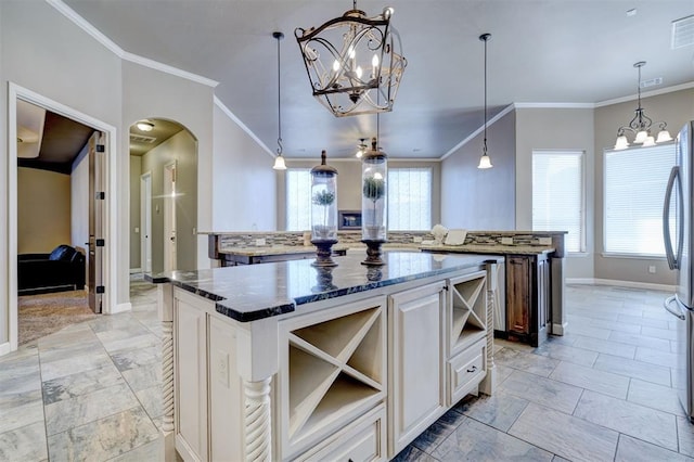 kitchen with an inviting chandelier, arched walkways, dark stone countertops, and a center island