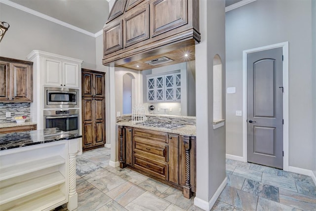 kitchen featuring arched walkways, stainless steel appliances, a high ceiling, ornamental molding, and light stone countertops