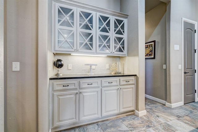 bar featuring baseboards, a dry bar, and decorative backsplash