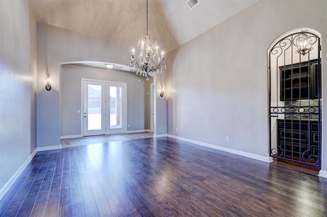 unfurnished room featuring arched walkways, dark wood finished floors, visible vents, a chandelier, and baseboards