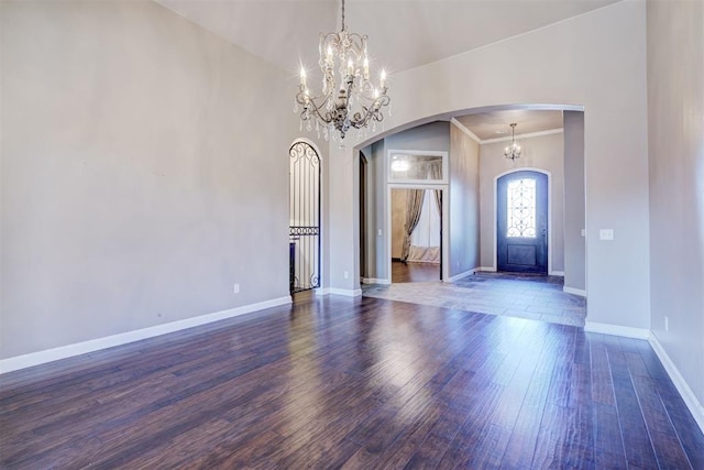 entryway with dark wood-style floors, baseboards, arched walkways, and a notable chandelier