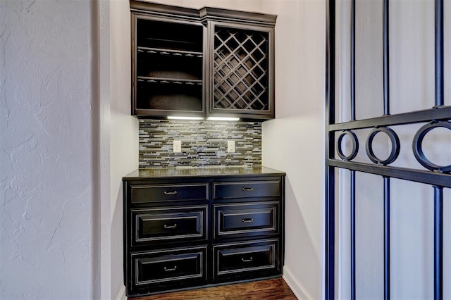 bar featuring baseboards, a dry bar, dark wood-type flooring, and decorative backsplash