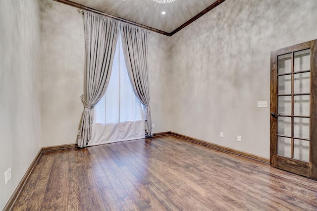 spare room featuring wood finished floors, a towering ceiling, and baseboards