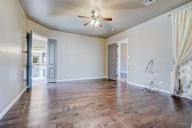 spare room featuring ceiling fan, dark wood finished floors, visible vents, and baseboards