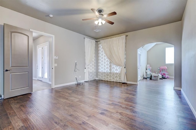 unfurnished room with visible vents, baseboards, a ceiling fan, arched walkways, and wood finished floors