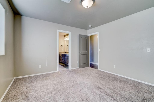 unfurnished bedroom with light colored carpet, connected bathroom, and baseboards