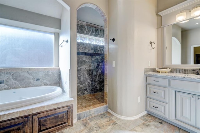 full bath with vanity, walk in shower, a bath, and baseboards