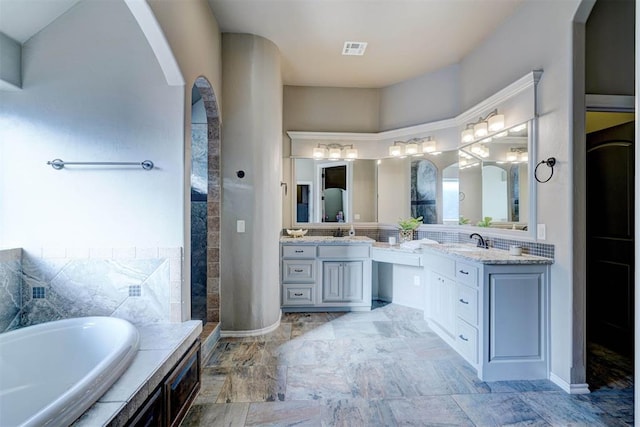 bathroom featuring visible vents, a bath, and vanity