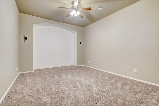 unfurnished room featuring arched walkways, carpet floors, visible vents, baseboards, and a ceiling fan