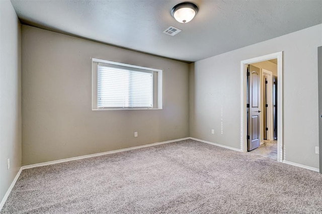 spare room with light carpet, baseboards, and visible vents