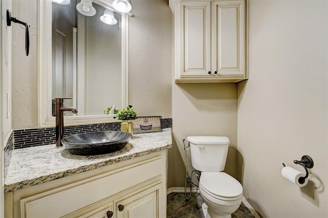 half bathroom with toilet, vanity, and baseboards