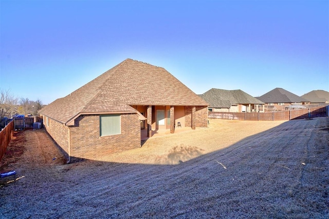 back of house with a fenced backyard, cooling unit, a shingled roof, and brick siding