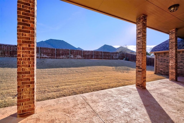 view of yard with a fenced backyard, a mountain view, and a patio