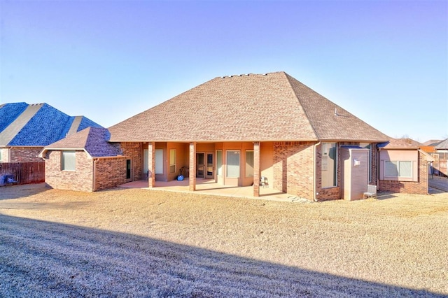 back of house featuring a patio area, a shingled roof, fence, and brick siding