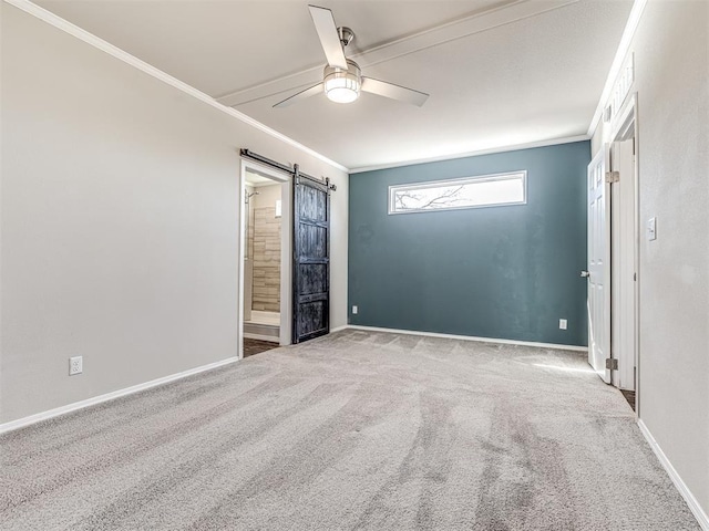 spare room with a barn door, light colored carpet, a ceiling fan, baseboards, and ornamental molding