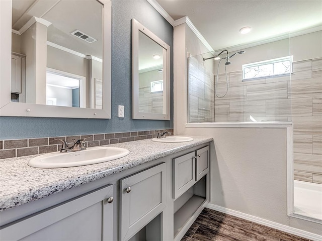 bathroom featuring crown molding, visible vents, a sink, and double vanity