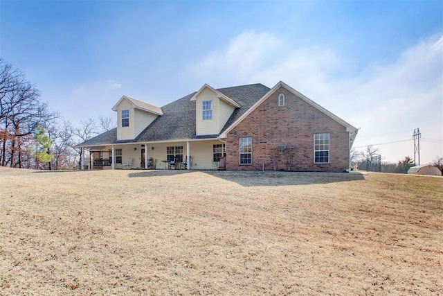 rear view of property with brick siding and a lawn