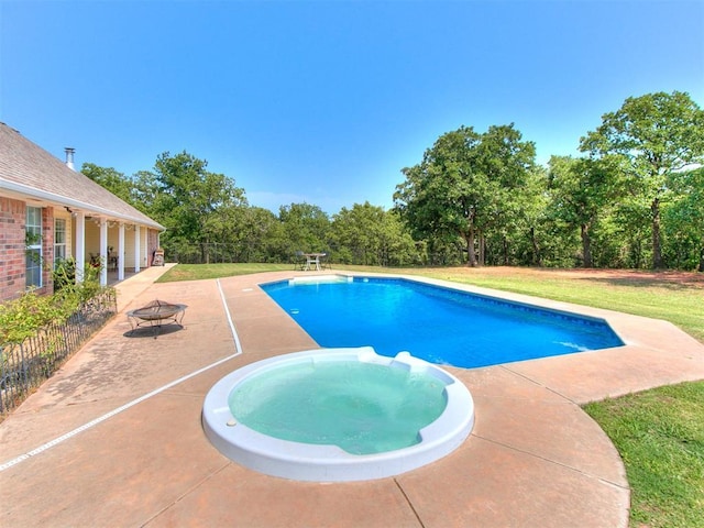 view of pool featuring a fire pit, a patio, fence, a yard, and a pool with connected hot tub