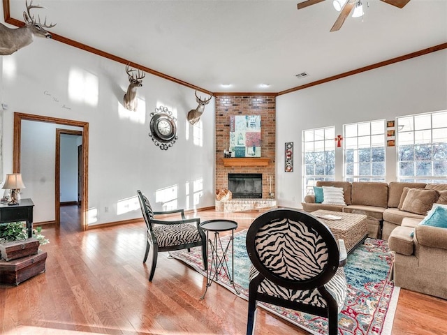 living area featuring a healthy amount of sunlight, light wood-style floors, a fireplace, and visible vents