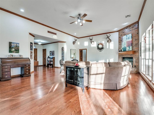 living room featuring a brick fireplace, visible vents, ceiling fan, and wood finished floors