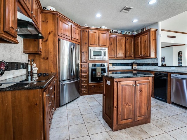 kitchen with a center island, visible vents, appliances with stainless steel finishes, light tile patterned flooring, and dark stone countertops