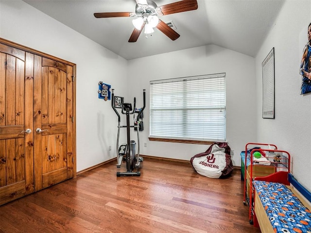 exercise room featuring a ceiling fan, baseboards, vaulted ceiling, and wood finished floors