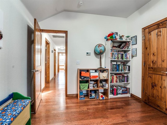 hall featuring visible vents, vaulted ceiling, baseboards, and wood finished floors