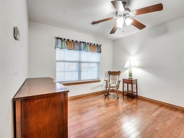 sitting room featuring light wood-type flooring, ceiling fan, and baseboards