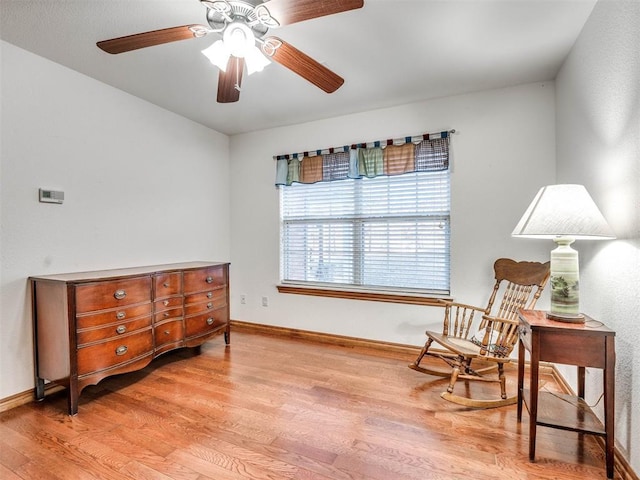 living area featuring light wood-type flooring, baseboards, and a ceiling fan