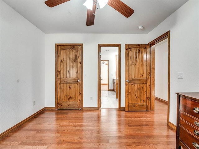 unfurnished bedroom featuring ceiling fan, light wood-style flooring, baseboards, and ensuite bath