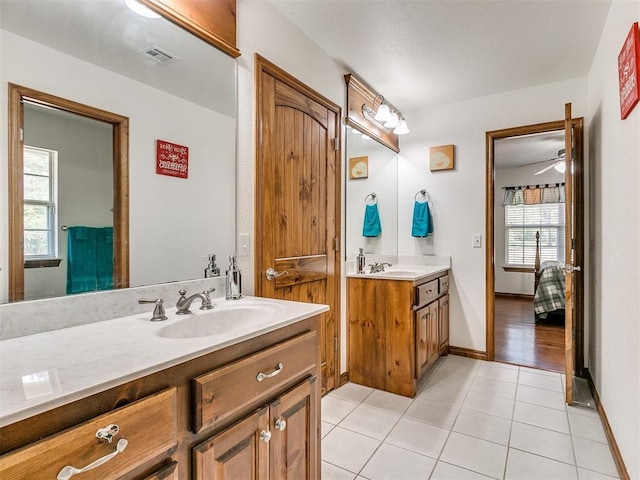 ensuite bathroom featuring tile patterned flooring, two vanities, a sink, visible vents, and ensuite bath